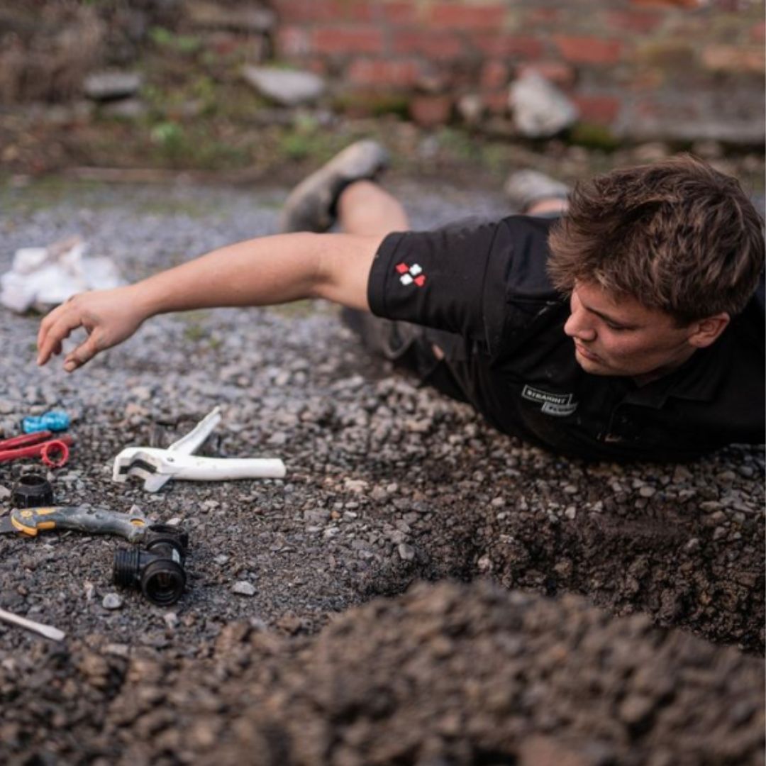 Plumber lying on ground working on drains