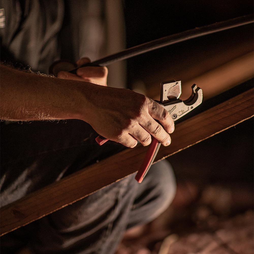 Hands working on pipes under house